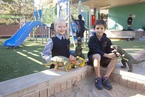 students playing with dinosaurs at school playground