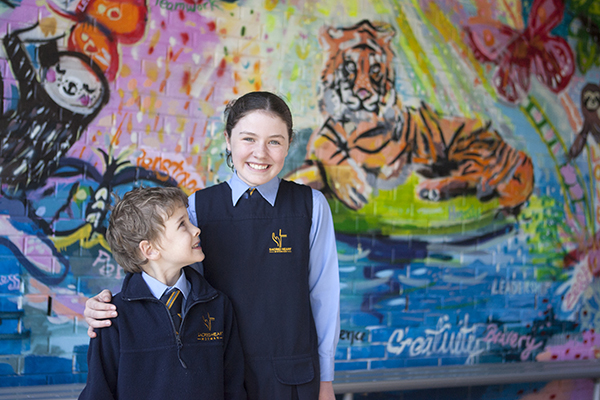 students standing in front of school mural